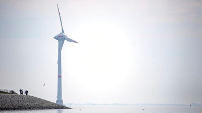 Cyclists ride along the dyke in Emden, Germany, Wednesday, June 3, 2020. The German government wants to increase offshore wind power capacity five-fold by 2040 as part of its plan to wean the country off fossil fuels. Cabinet on Wednesday agreed a bill that would set a goal of 40 Gigawatts of installed offshore wind power capacity in 20 years, from about 7.5 Gigawatts at present. It also raised the target for 2030 from 15 Gigawatts to 20.