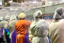 In this April photo, Tyson Foods workers wear protective masks and stand between plastic dividers at the company's Camilla, Georgia poultry processing plant.