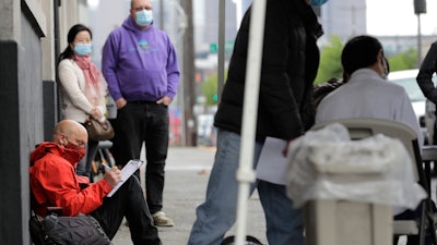 Glen Buhlmann, lower left, fills out a job application during a walk- and drive-up job fair in Seattle, May 16, 2020.