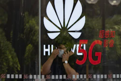 A worker wearing a mask speaks on the phone near the Huawei logo in a store in Beijing, July 15, 2020.