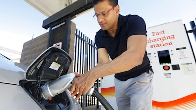 Man charges electric car at fast charging station.