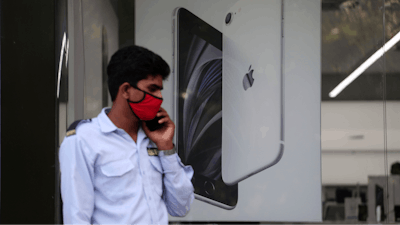 A security officer talks on a phone in front of an image of an iPhone displayed at an Apple store in Ahmedabad, India.