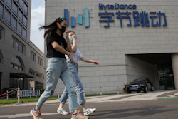 Women wearing masks pass by the ByteDance headquarters in Beijing, Aug. 7, 2020.