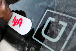 A Lyft logo is installed on a Lyft driver's car next to an Uber sticker.