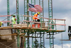 Workers on scaffolding lay blocks.