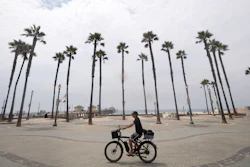 A cyclist rides through the pier plaza in Huntington Beach, Calif.