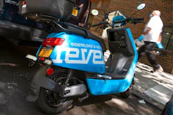 A man passes a parked Revel scooter on New York's Upper West Side, Tuesday, July 28, 2020. The moped sharing startup Revel suspended its New York City service Tuesday, July 28, 2020 after its second customer death in 10 days. The company's blue scooters, which require no training to rent, had been seen as an alternative to taxis and subways during the coronavirus pandemic.