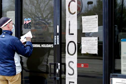 In this April 30, 2020 file photo, a man writes information in front of Illinois Department of Employment Security in Chicago. It's the paradox of a pandemic that has crushed the U.S. economy: There are 12.9 million job losses and a dangerous rash of closed business, yet the personal finances of many Americans have remained strong, and in some ways have even improved. A new poll by The Associated Press-NORC Center for Public Affairs Research shows that 45% of Americans say they’re setting aside more money than usual. Twenty-six percent are paying down debt faster than they were before the coronavirus pandemic. In total, about half of Americans say they’ve either saved more or paid down debt.