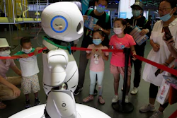 Visitors wearing masks to protect from the coronavirus look at a robot displayed at a trade fair in Beijing.