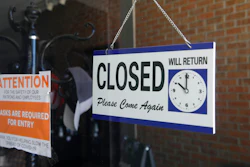 A closed sign hangs in the window of a barber shop.