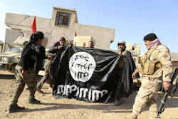 Iraqi Army soldiers celebrate as they hold a flag of the Islamic State group captured during a military operation to regain control of a village outside Mosul, Iraq, Nov. 29, 2016.