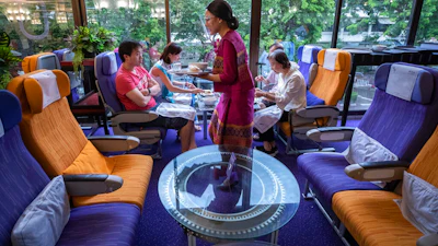 A flight attendant serves meals in a flight-themed restaurant at the Thai Airways head office.