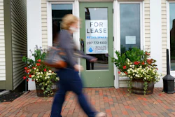 A shopper walks by one of several vacant retail spaces among the outlet shops in Freeport, Maine.