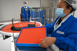 A worker feeds vials for production of SARS CoV-2 Vaccine for COVID-19
