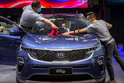 Staff members wearing face masks to protect against the coronavirus clean a Kia KX5 compact SUV.