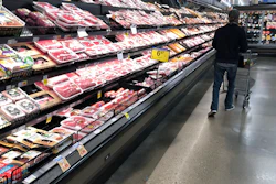 In this May 10, 2020 photo, a shopper pushes his cart past a display of packaged meat in a grocery store in southeast Denver.
