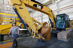 In this Sept. 18, 2019, photo a Puckett Machinery Company technician walks past a new heavy duty Caterpillar excavator that awaits modification at Puckett Machinery Company in Flowood, Miss. Caterpillar is reporting a third-quarter profit of $668 million and topped most expectations, though demand for its equipment is being driven down by the pandemic. The Deerfield, Illinois, company reported a profit Tuesday, Oct. 27, 2020, of $1.22 per share.