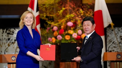 British International Trade Secretary Liz Truss, left, and Japanese Foreign Minister Toshimitsu Motegi exchange agreement documents for economic partnership between Japan and Britain at Iikura Annex of the Foreign Ministry in Tokyo, Friday, Oct. 23, 2020. Japan and Britain signed a bilateral free trade deal Friday in the the first such major post-Brexit deal, reducing tariffs on Yorkshire lamb sold in Japan, as well as auto parts for Japan’s Nissan plant.