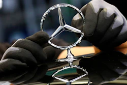 In this Thursday, April 30, 2020 file photo, an employee attaches a Mercedes emblem as he works on a Mercedes-Benz S-class car at the Mercedes plant in Sindelfingen, Germany. Daimler, maker of Mercedes-Benz vehicles, is reporting third-quarter earnings on Friday Oct. 22, 2020.
