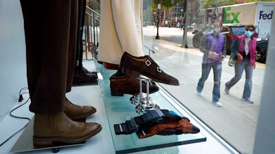 Passers-by examine a storefront window, Tuesday, Sept. 15, 2020, in Boston's fashionable Newbury Street shopping district. Retail sales rose in September for the fifth month in a row, as Americans spent more on clothing, cars and sporting goods. The U.S. Commerce Department said Friday, Oct. 16, that retail sales grew 1.9% last month.