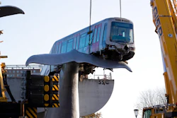 A salvaging crew prepares to attach chains to lift to a metro train carriage off the whale's tail.