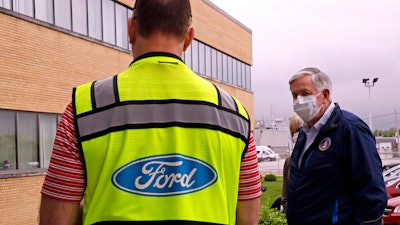 Missouri Gov. Mike Parson talks to a Ford representative outside Ford's Kansas City Assembly Plant.