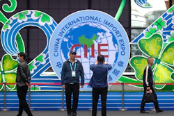 A visitor poses for photos in front of a display at the China International Import Expo in Shanghai, Nov. 5, 2020.