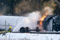 A firefighter sprays foam on a burning, derailed train car Tuesday, Dec. 22, 2020, in Custer, Wash. Officials say seven train cars carrying crude oil derailed and five caught fire north of Seattle and close to the Canadian border. Whatcom County officials said the derailment occurred in the downtown Custer area, where streets were closed and evacuations ordered during a large fire response.