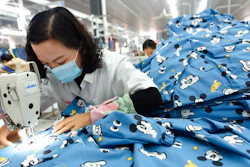 In this Oct. 27, 2020, file photo, a woman wearing a mask works in a garment factory in Donghai county in east China's Jiangsu province. China’s manufacturing activity improved in December, 2020 but at its weakest rate in three months as the economy recovered from the coronavirus pandemic while its trading partners struggled with rising infections, according to two surveys.