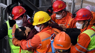 In this photo released by Xinhua News Agency, rescuers carry a miner who was trapped in a mine to an ambulance in Qixia City in east China's Shandong Province.