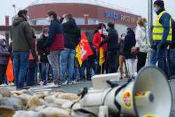 Striking workers gather outside the French pharmaceutical company Sanofi headquarters in Marcy l'Etoile, central France, Tuesday, Jan.19, 2021. Employees of pharmaceutical company Sanofi stage a protest against planned redundancies that they say could slow the fight against the Coronavirus pandemic . Sanofi had been developing Covid vaccines but will not be ready to roll out until late 2021.
