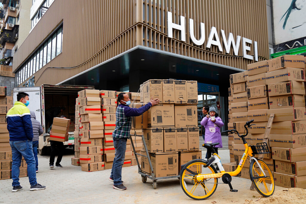 Workers move boxes of computers on a street in Wuhan, China, Jan. 16, 2021.