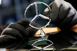 An employee attaches a Mercedes emblem to a Mercedes-Benz S-class car, Sindelfingen, Germany, April 30, 2020.