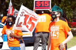 Cristian Cardona, right, an employee at a McDonald's, attends a rally for a $15 an hour minimum wage on Feb. 16 in Orlando, FL.