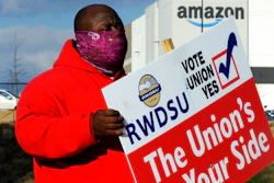 Michael Foster of the Retail, Wholesale and Department Store Union holds a sign outside an Amazon facility where labor is trying to organize workers on Tuesday, Feb. 9, 2021. For Amazon, a successful effort could motivate other workers to organize. But a contract could take years, and Amazon has a history of crushing labor organizing.