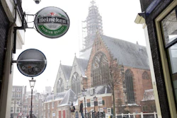 A Heineken sign sits on the facade of a bar, closed because of the coronavirus lockdown in Amsterdam, Sunday, Feb. 7, 2021. Dutch beer brewer Heineken said Wednesday it plans to cut 8,000 staff, nearly 10% of its global workforce, as part of a cost-cutting reorganization after a pandemic-dominated year that saw it sink to a net loss of 204 million euros ($248 million).