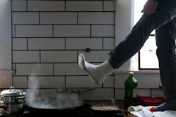 Jorge Sanhueza-Lyon stands on his kitchen counter to warm his feet over his gas stove Tuesday, Feb. 16, 2021, in Austin, Texas. Power was out for thousands of central Texas residents after temperatures dropped into the single digits when a snow storm hit the area on Sunday night.