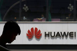 In this Thursday, May 16, 2019 file photo, a man is silhouetted near the Huawei logo in Beijing. Struggling under U.S. sanctions, Chinese tech giant Huawei has unveiled a new flagship foldable smartphone but says it will only be sold in China.