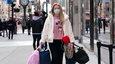 In this Dec. 10, 2020 file photo, a woman carries shopping bags in New York. The nation’s largest retail trade group is forecasting strong retail sales growth in 2021 that could surpass last year's pace as individuals get vaccinated and the economy reopens. The National Retail Federation anticipates that retail sales will grow between 6.5% and 8.2% to more than $4.33 trillion this year.