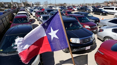 Hundreds of a vehicles are staged in a parking lot as people wait in line at a food and water distribution site in Houston.