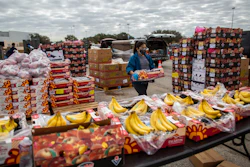 In this file photo, a volunteer carries food to be distributed during the Neighborhood Super Site food distribution event organized by the Houston Food Bank and HISD, in Houston.