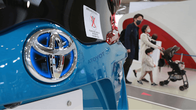 Visitors walk by a Toyota car displayed at its showroom in Tokyo.