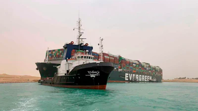 A boat navigates Egypt’s Suez Canal in front of the grounded Ever Green, March 24, 2021.