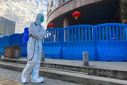 A worker carrying disinfecting equipment walks outside the Wuhan Central Hospital, Wuhan, China, Feb. 6, 2021.