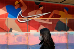 A woman wearing a mask passes by a Nike store in Beijing on Thursday, March 25, 2021. China's ruling Communist Party is lashing out at H&M and other clothing and footwear brands as it retaliates for Western sanctions imposed on Chinese officials accused of human rights abuses in the northwestern region of Xinjiang.