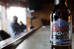 In this file photo, a bottle of Coors Light sits on the bar as a patron sips a beer at a tavern.