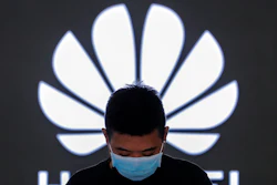 In this file photo, an employee wearing a face mask stands inside a Huawei flagship store in Beijing.