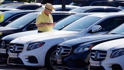 A shopper looks over a line of 2020 sedans at a Mercedes Benz dealership, Littleton, Colo., Oct. 4, 2020.