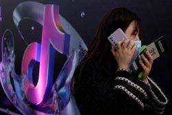 A woman speaks on her phone near the logo for Douyin in Beijing. China's internet watchdog said it had found Bytedance's Douyin, Microsoft Bing, LinkedIn and 102 other apps were engaged in improper collection and use of data and ordered them to fix the problem.
