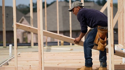 A carpenter aligns a beam for a wall frame at a new house site in Madison County, Mississippi.